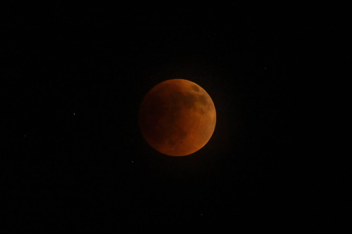 As in sunsets, the blue light is scattered away and mainly red light is left to hit the moon.